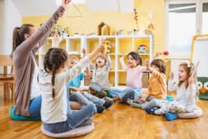 Kindergarten teacher with children sitting on the floor having music class, using various instruments and percussion.