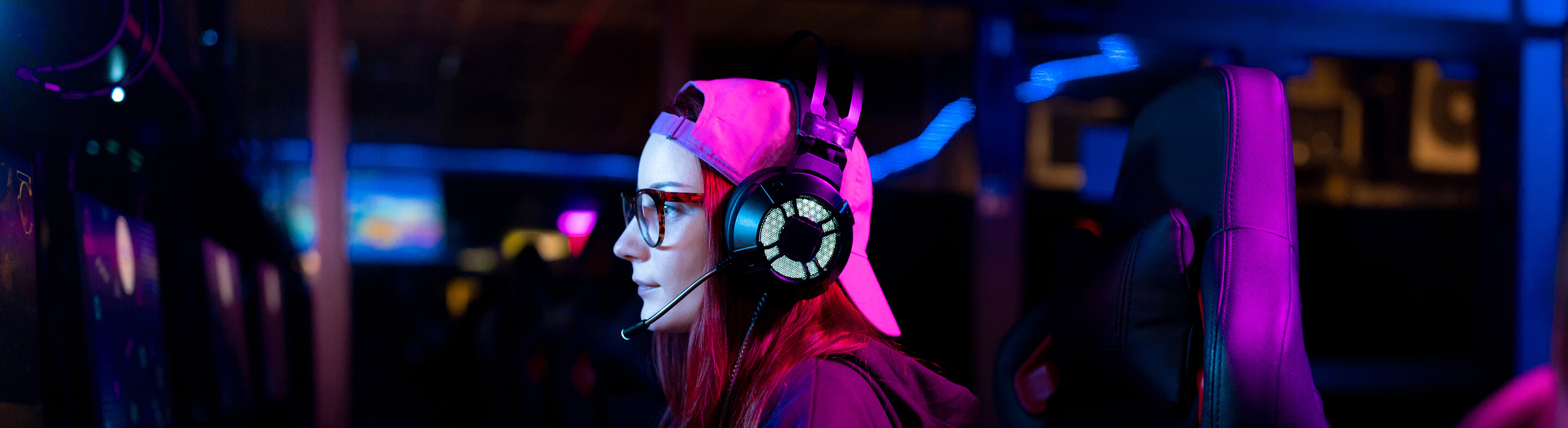 A student plays Esports on a computer while wearing noise-canceling headphones. 