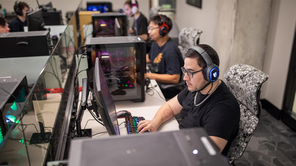 A close-up of an Esports team member concentrating, hands on keyboard, while wearing a headset.